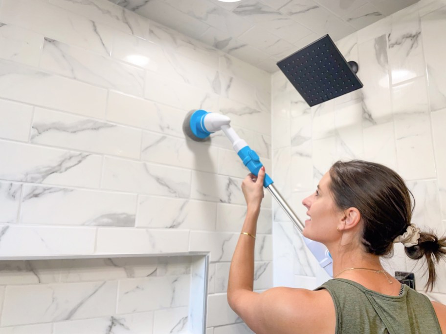 woman using an oraimo spin scrubber to clean her shower walls