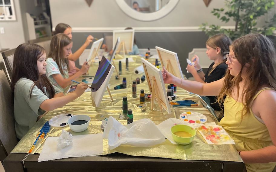 girls sitting at table having a canvas paint party