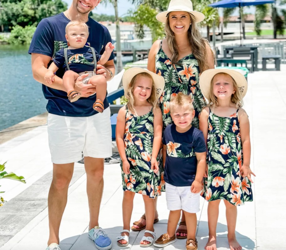 family standing on beach in matching tropical print outfits