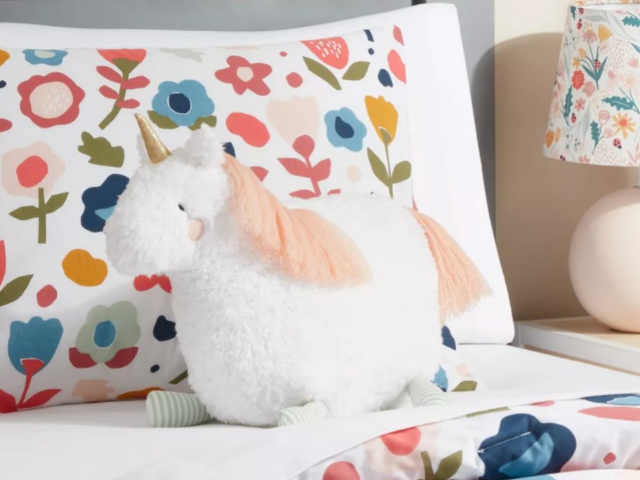 unicorn shaped pillow on floral bed