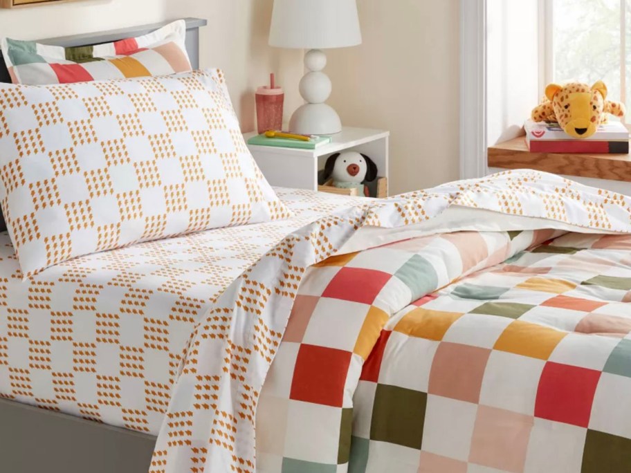 yellow and white checkered sheet set on bed with comforter 