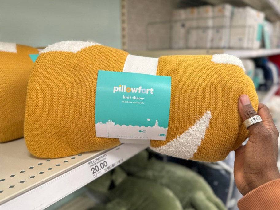 hand holding yellow blanket on shelf in target store