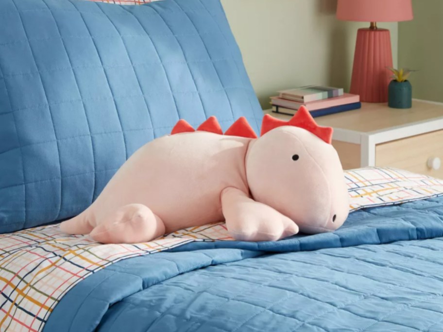 pillowfort pink weighted dinosaur pillow on bed
