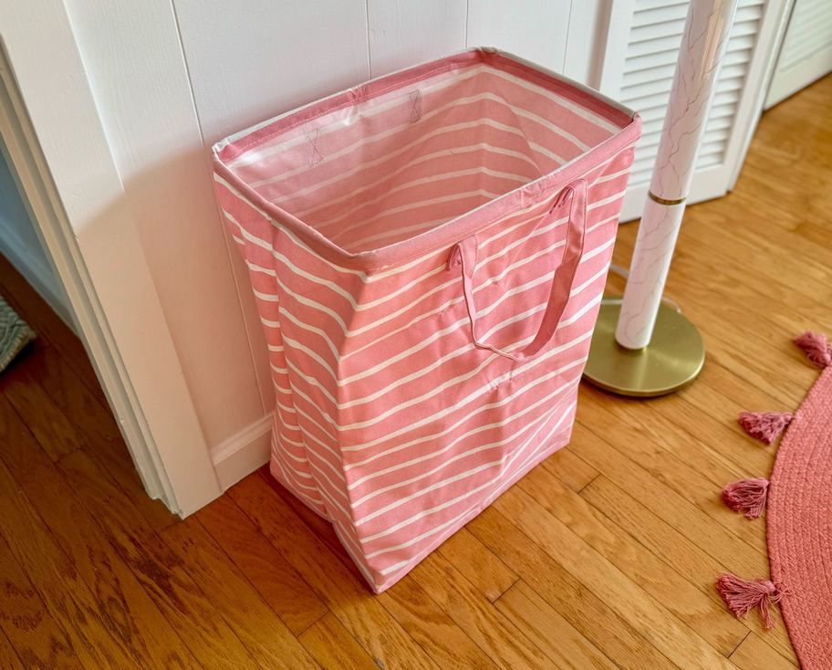pink and white stripe laundry basket sitting on wood floor