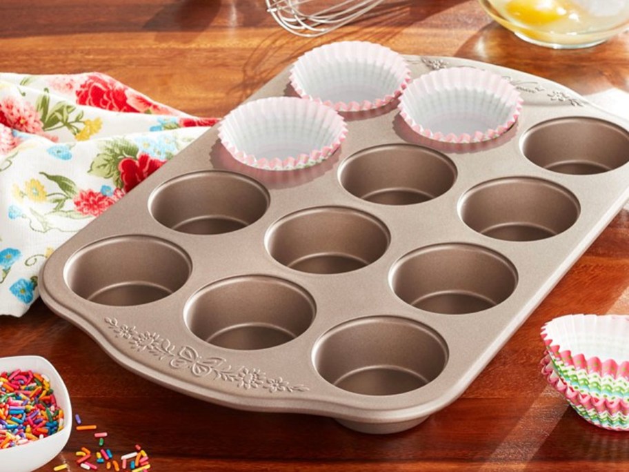 steel muffin pan on table with muffin liners in pan
