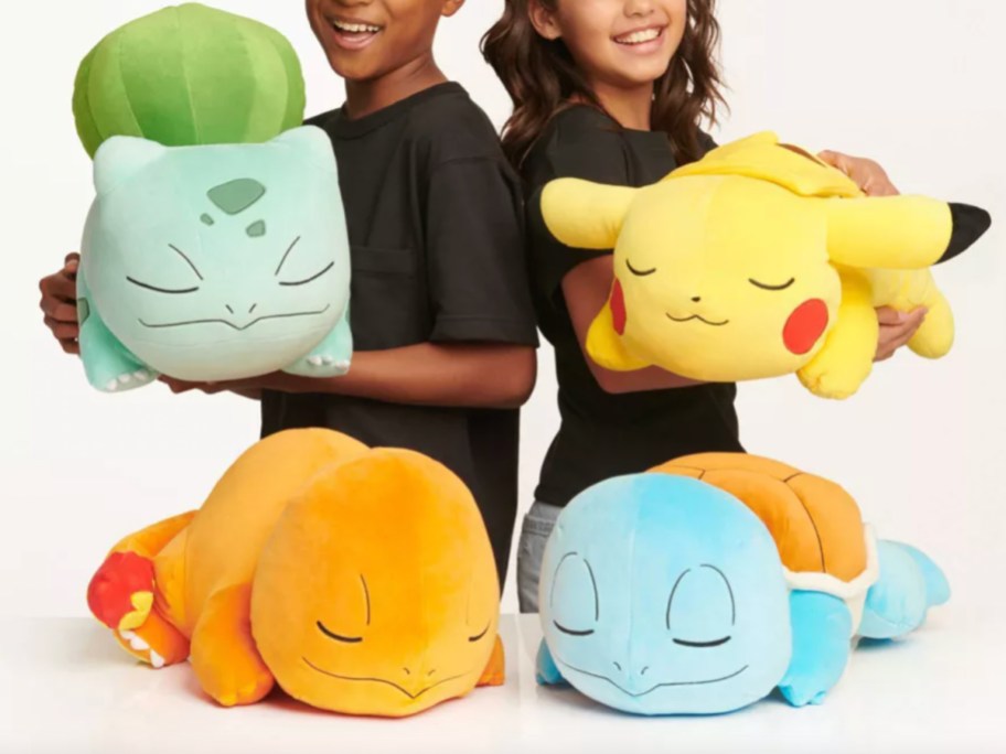 two kids holding big pokemon pillows 