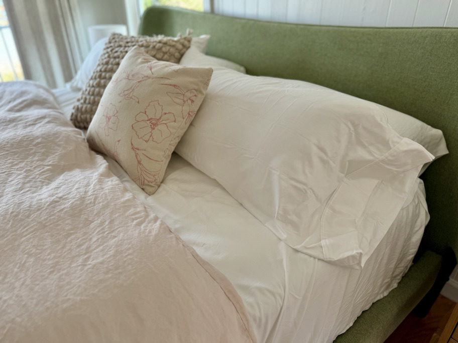 close up of bed with white sheets and two throw pillows