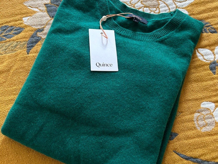 green cashmere sweater laying on floral comforter