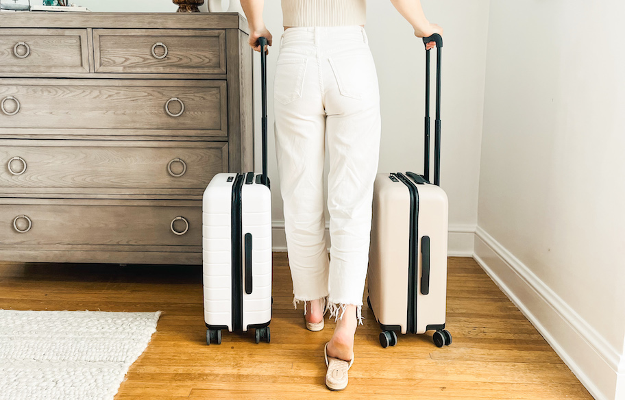 woman walking in room with white and beige carry on luggage suitcases