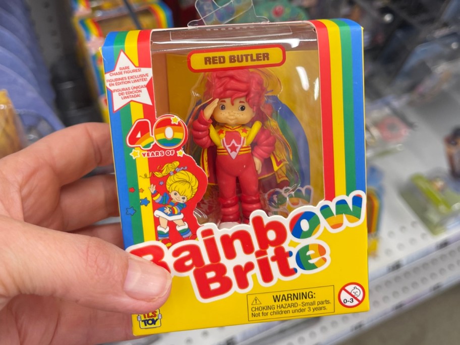 hand holding a box with a Rainbow Brite Red Butler Mini Doll Figure in it