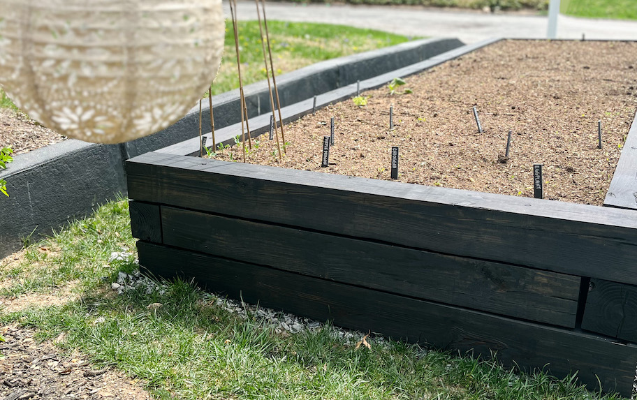 raised garden bed with slate stakes with different names of vegetables 