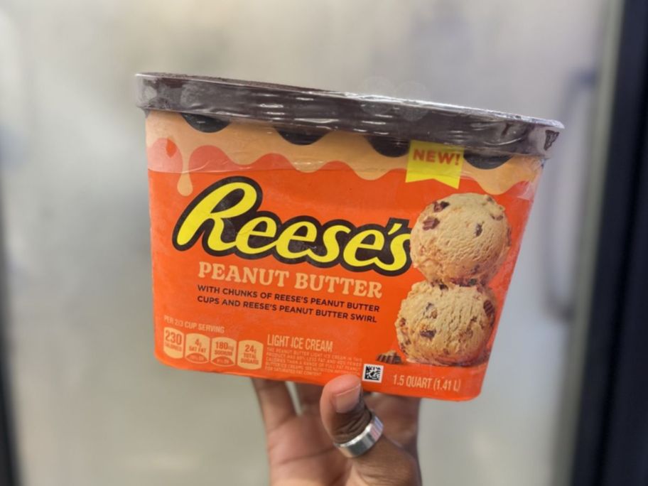 reese's tub of ice cream being held up next to store freezer