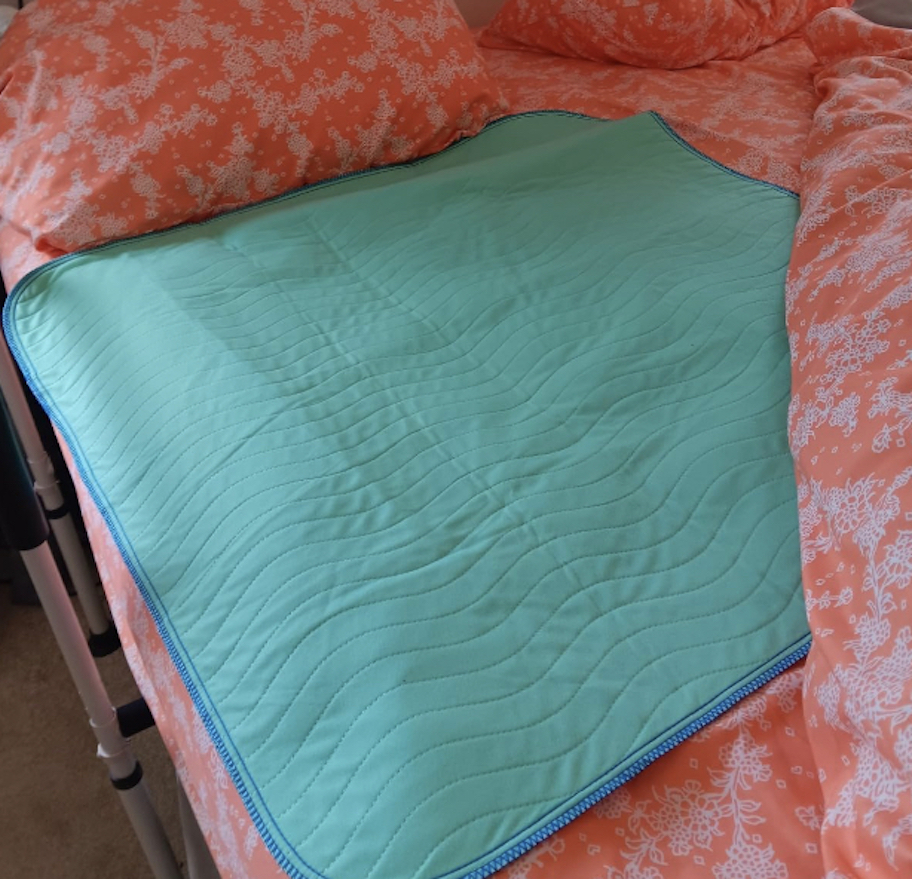 blue washable underpad on bright colored orange pink bedding