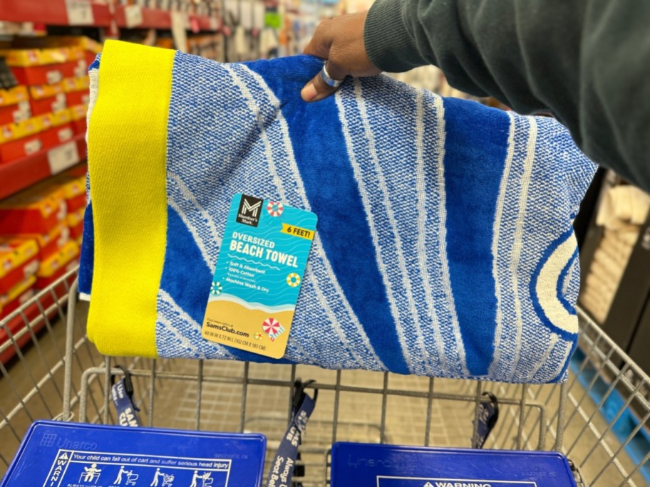hand holding a beach towel with a blue white and yellow design