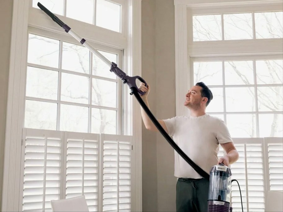 man using shark lift away vacuum to clean windows