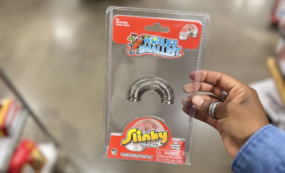 a womans hand holding a packaged worlds smallest slinky 