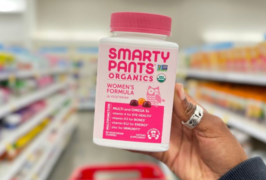 a womans hand holding a big bottle of smartpants womens vitamins