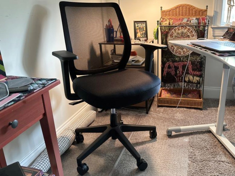 black office chair with mesh back in office next to white desk