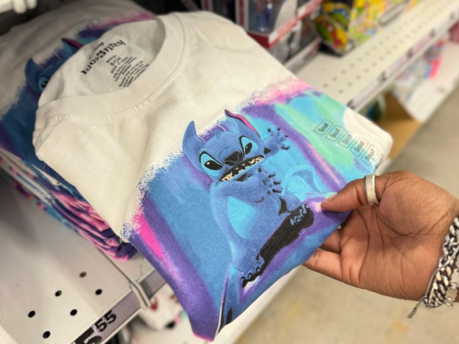 a womans hand holding a stitch dolphin tee