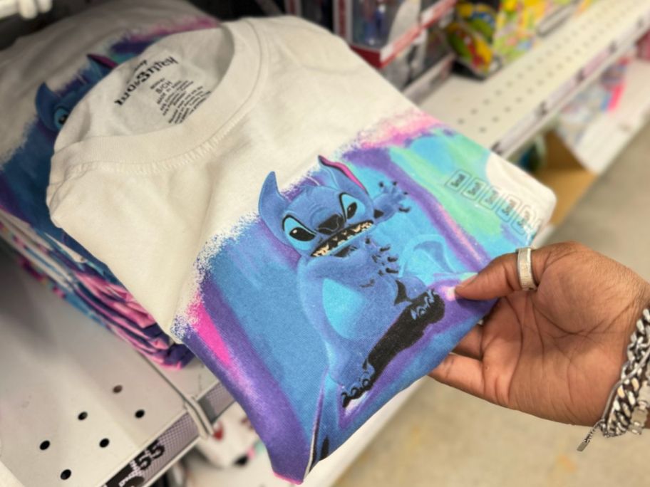 a womans hand holding a stitch dolphin tee