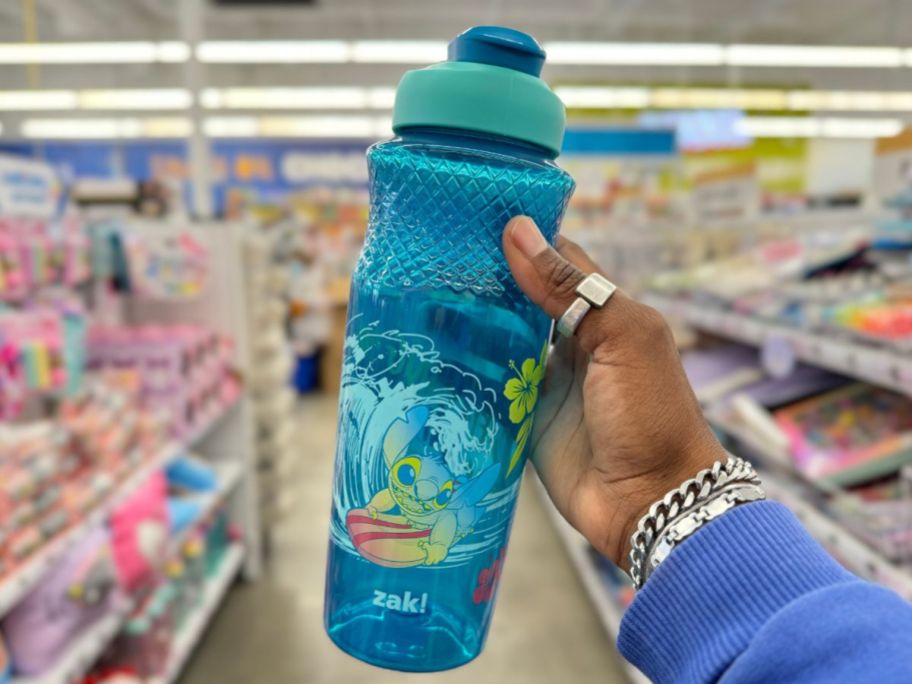 a womans hand holding a blue stitch water bottle