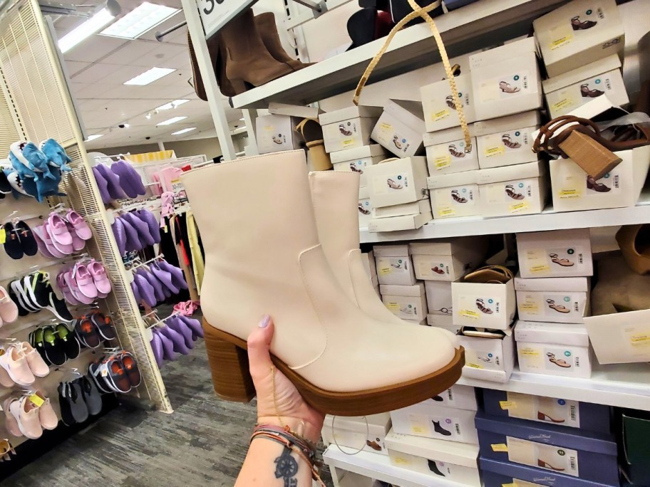 hand holding up a pair of off white women's boots in store