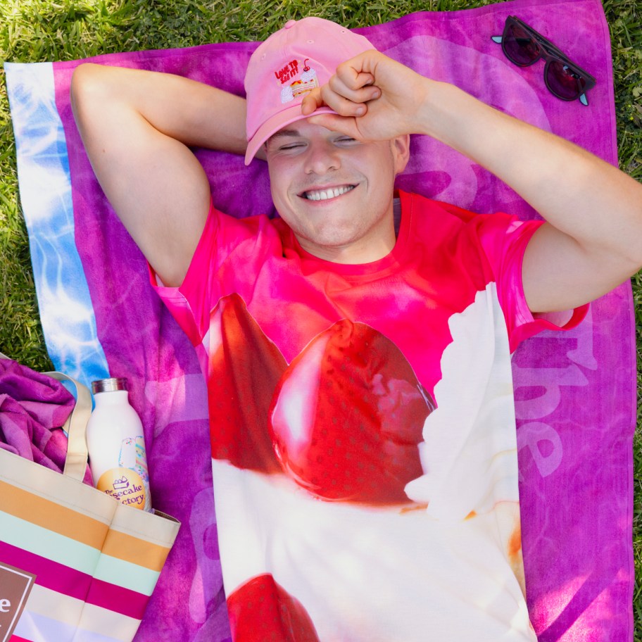 person lying on purple towel with Cheesecake Factory merchandise