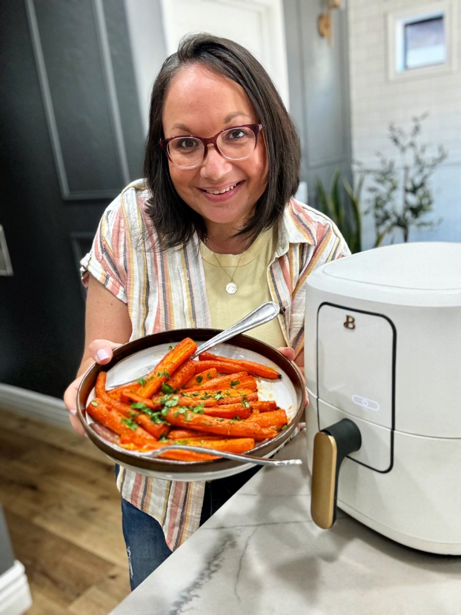 woman holding a plate of air fryer glazed carrots
