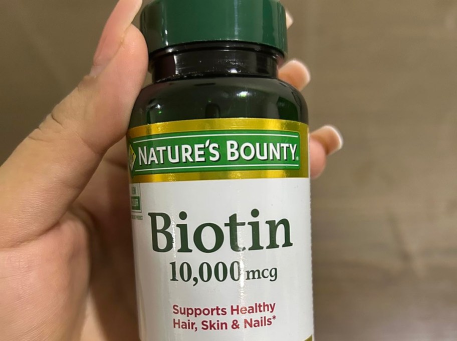 woman holding biotin vitamins in hand