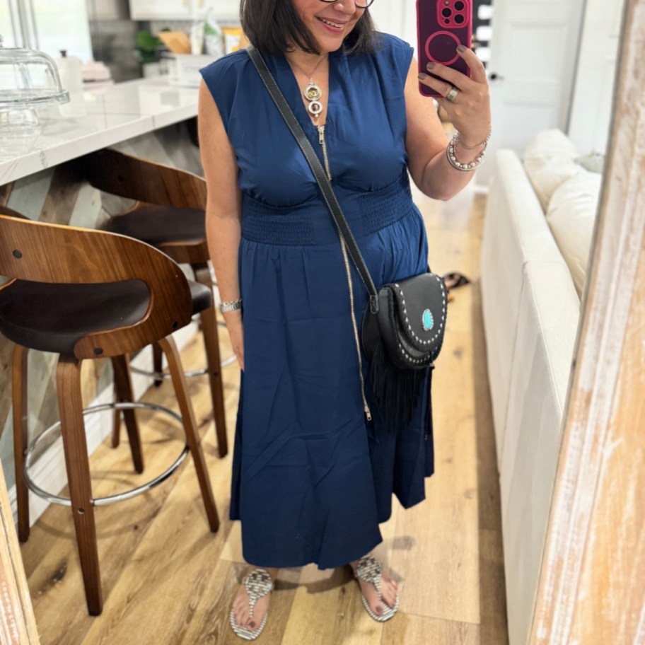 a woman in a blue cap sleeve midi dress taking a selfie
