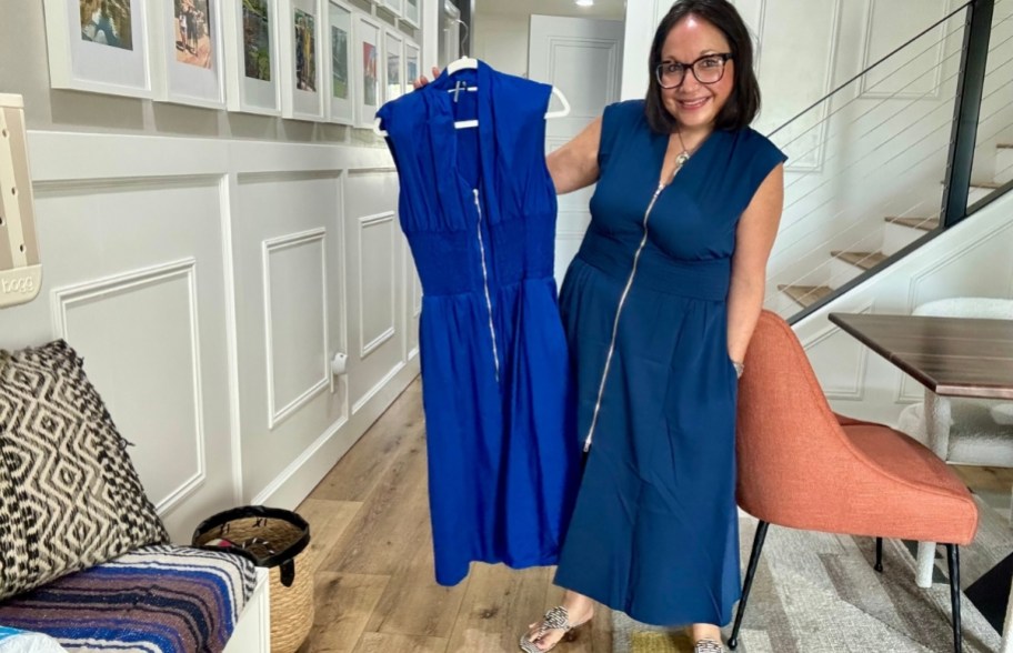 a woman in a blue cap sleeve midi dress holding another blue cap sleeve midi dress by the hanger in comparison