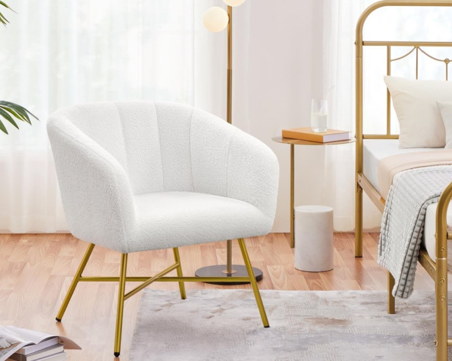 white boucle chair with gold legs next to gold bed