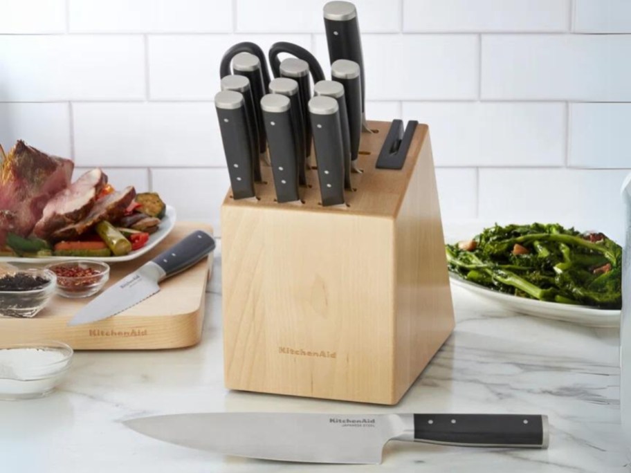 KitchenAid knife block set on counter next to cutting board with meat on it and a bowl of veggies 