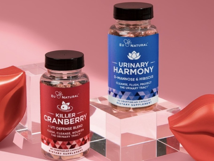 bottles of EU Natural Killer Cranberry and Urinary Harmony supplements on a pink background