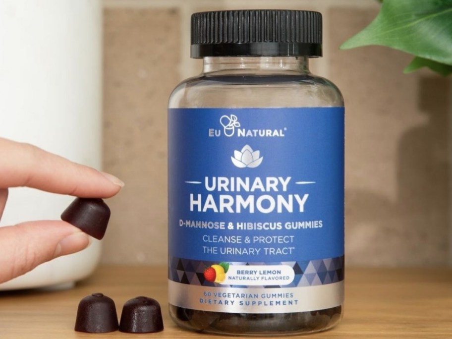bottle of Urinary Harmony gummies with a hand picking up a gummy