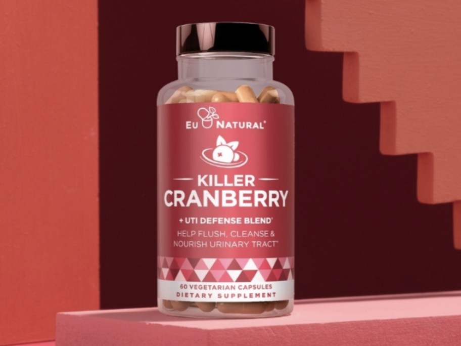 bottle of Killer Cranberry UTI supplements on a dark red background