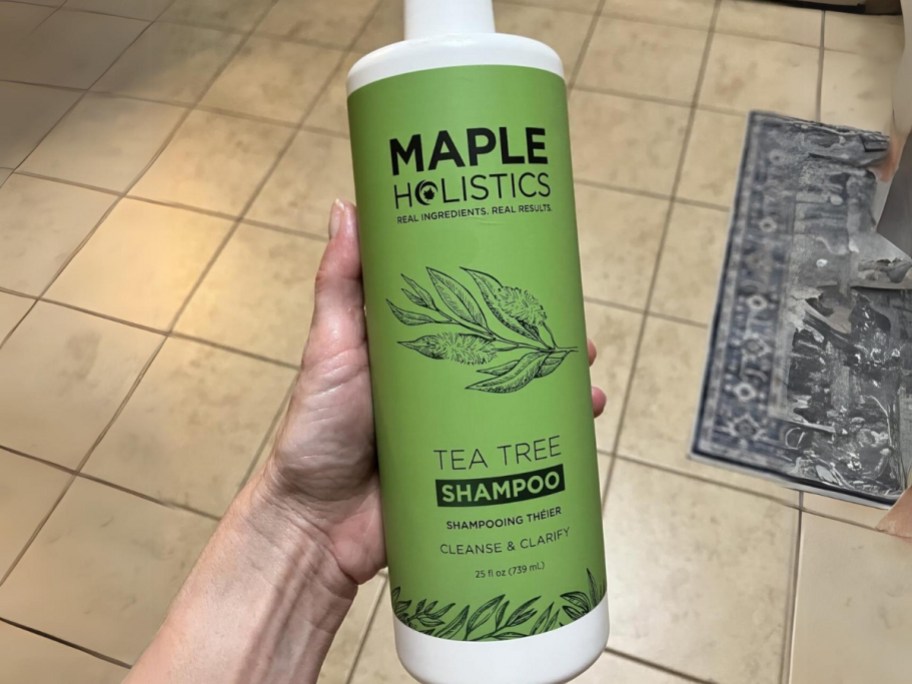 hand holding a large bottle of Maple Holistics Tea Tree Oil Shampoo 