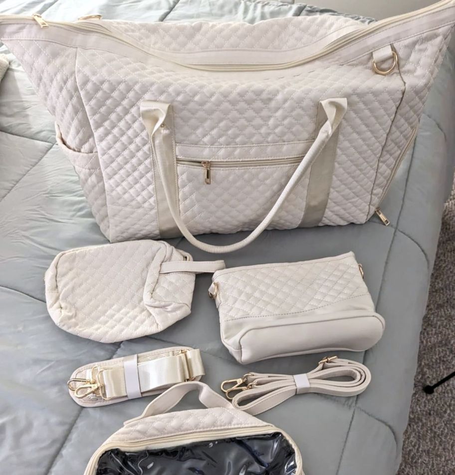 4 piece travel duffle set in ivory quilted poly fabric shown with with detachable strap, dopp kit, cosmetic bag and shoulder bag with detachable crossbody strap