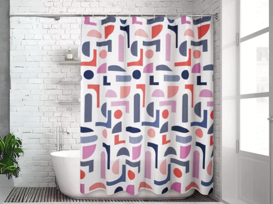 shower curtain hanging on a shower/bath tub with bright orange, purple and blue color design