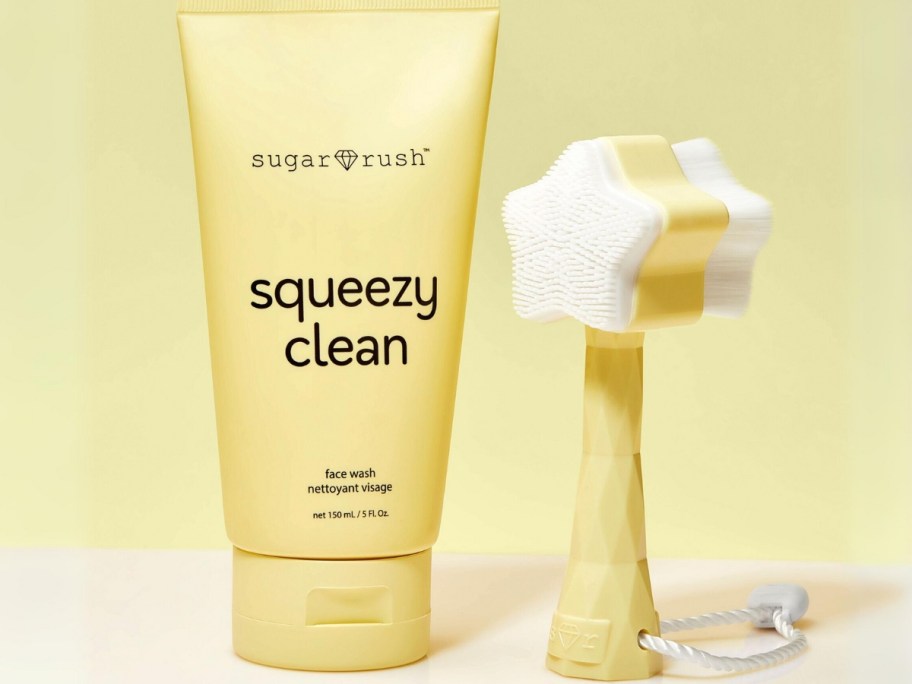 yellow bottle of Tarte Sugar Rush Squeezy Clean Face Wash next to a wash brush