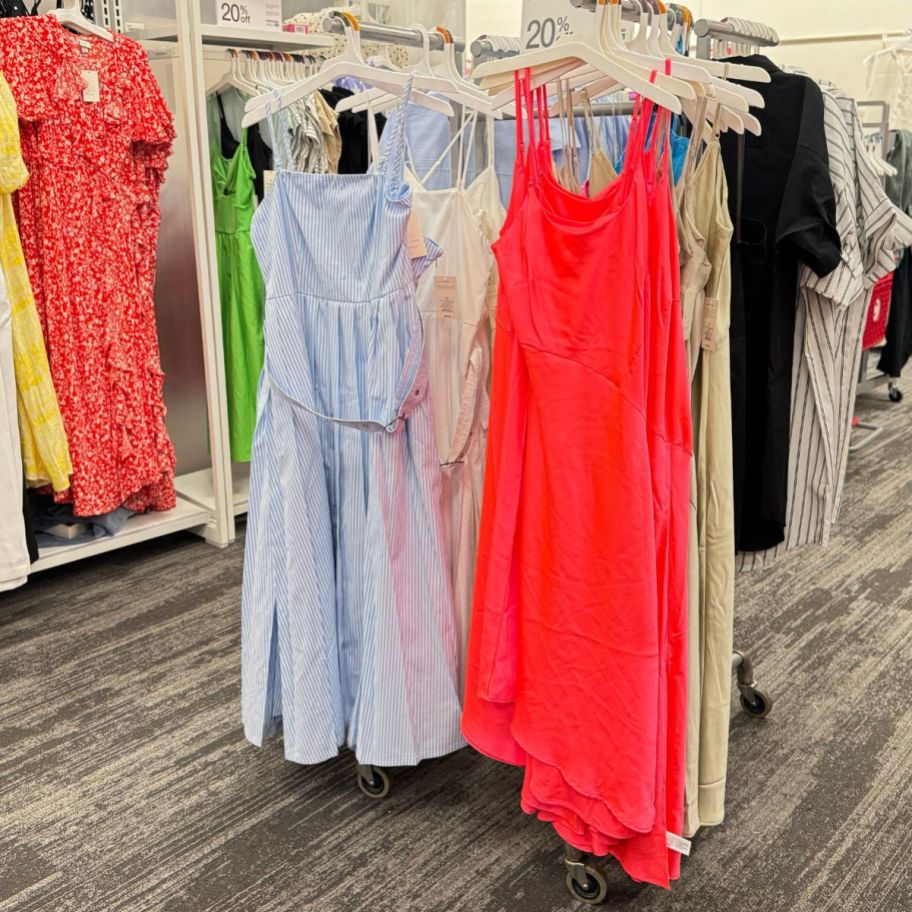 a rack of brightly colored midi sundresses in a store 