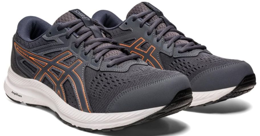 a pair of gray mens running shoes with orage accents