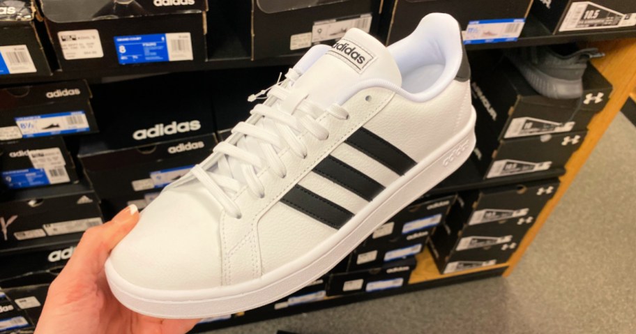 Woman holding a pair of Adidas court shoes inside store