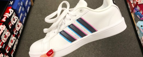 hand holding up white adidas sneaker with white, pink, and blue stripes