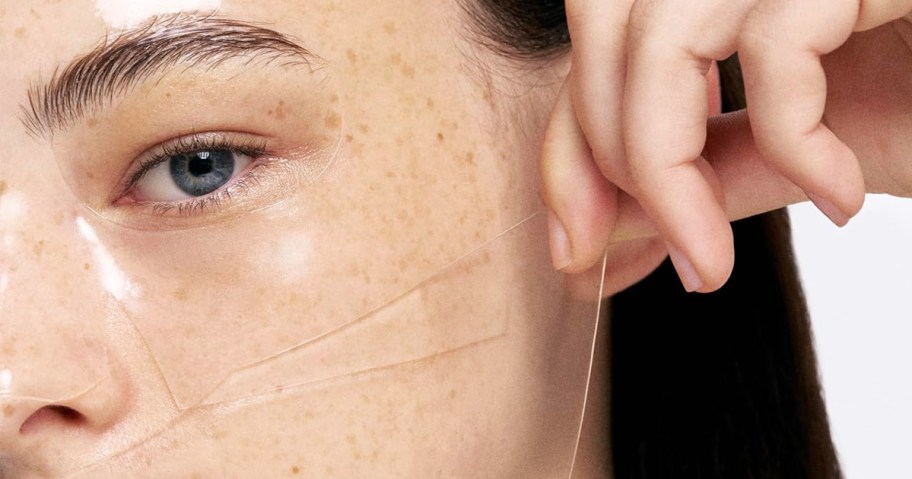 woman peeling mask off her face