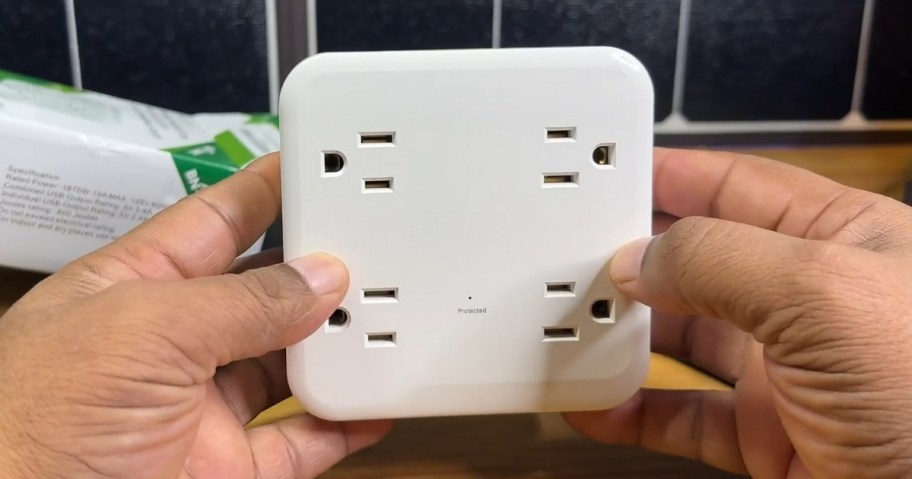 person's hands holding a white outlet extender with multiple outlets