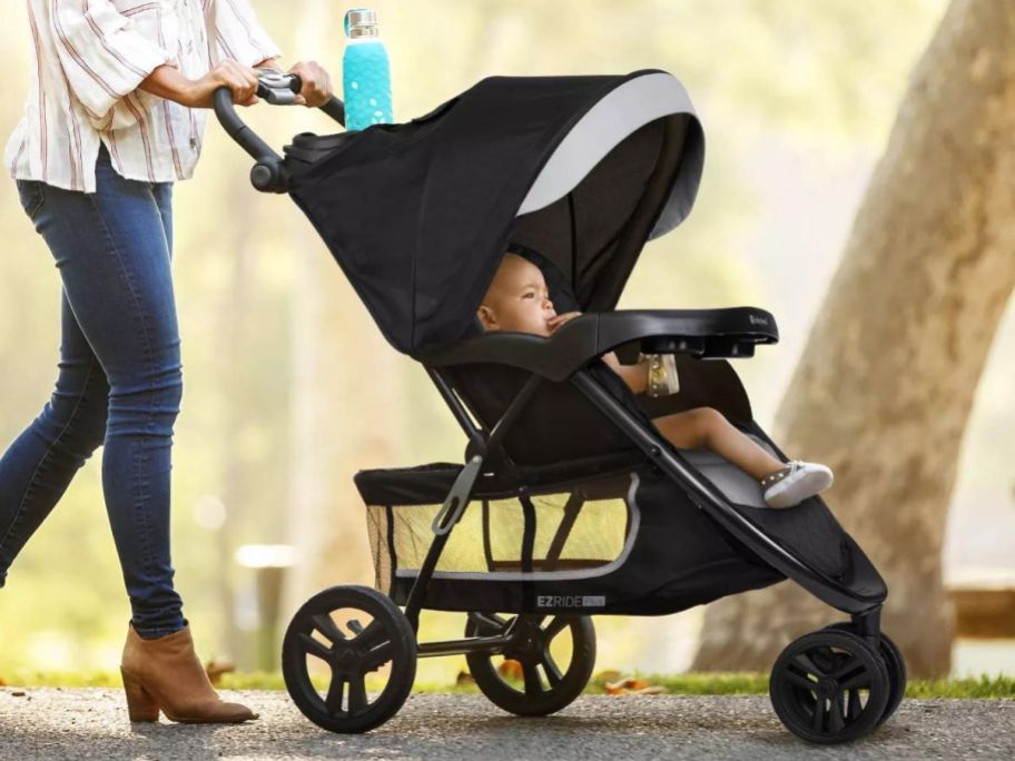 A woman pushing a child in a Baby Trend EZ Ride PLUS Travel System stroller