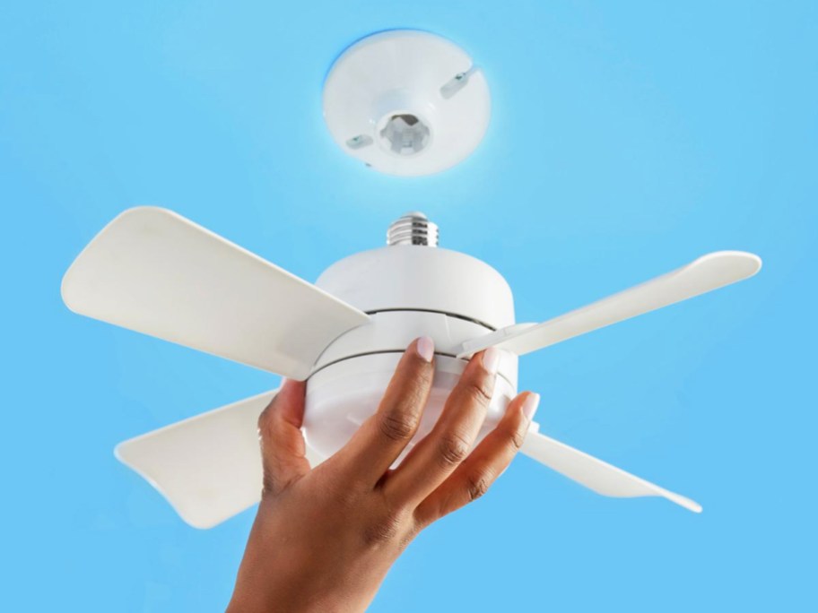hand installing a white ceiling fan into light socket