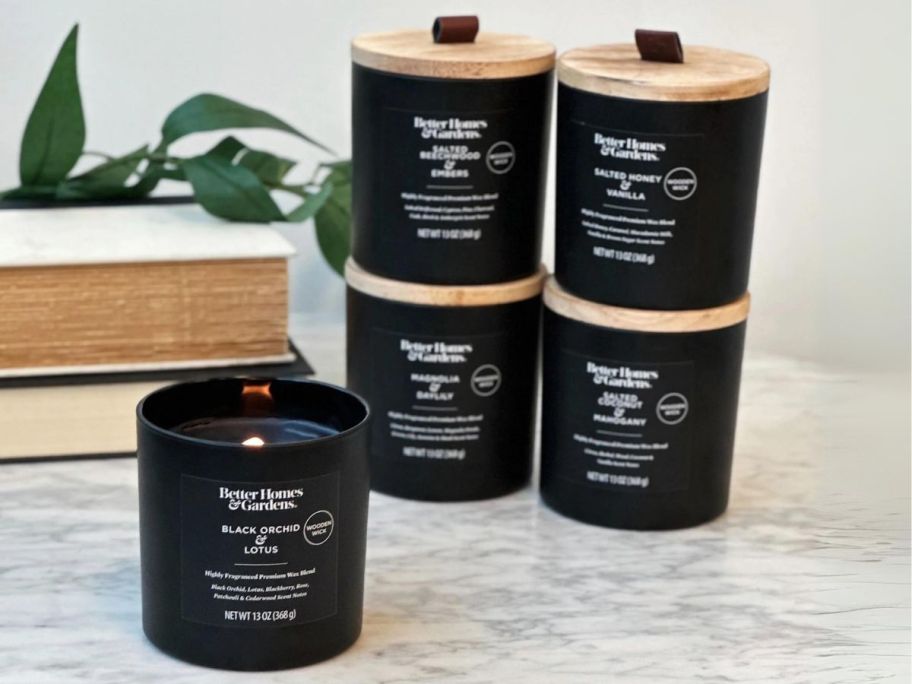 Better Homes & Gardens 13oz Wooden Wick Jar Candle on bathroom counter with 4 stacked to the side