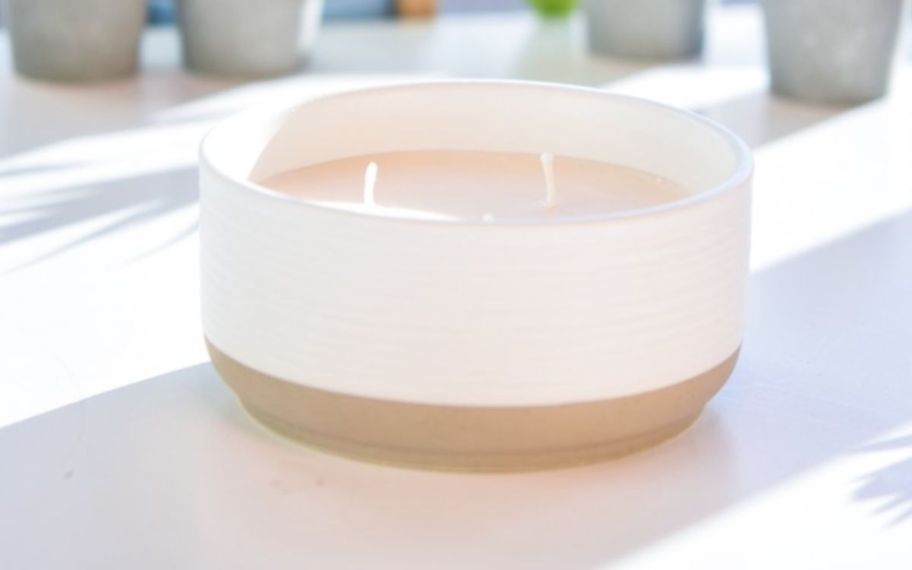 a 3 wick candle in a white ceramic dish